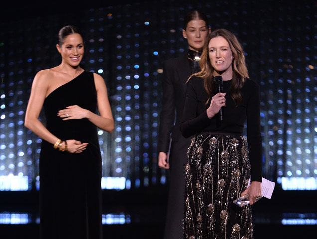 Clare Waight Keller is watched by Meghan, Duchess of Sussex and Rosamund Pike as she speaks on stage after receiving the award for British Designer of the Year Womenswear Award for Givenchy during The Fashion Awards 2018 In Partnership With Swarovski at Royal Albert Hall on December 10, 2018 in London, England.