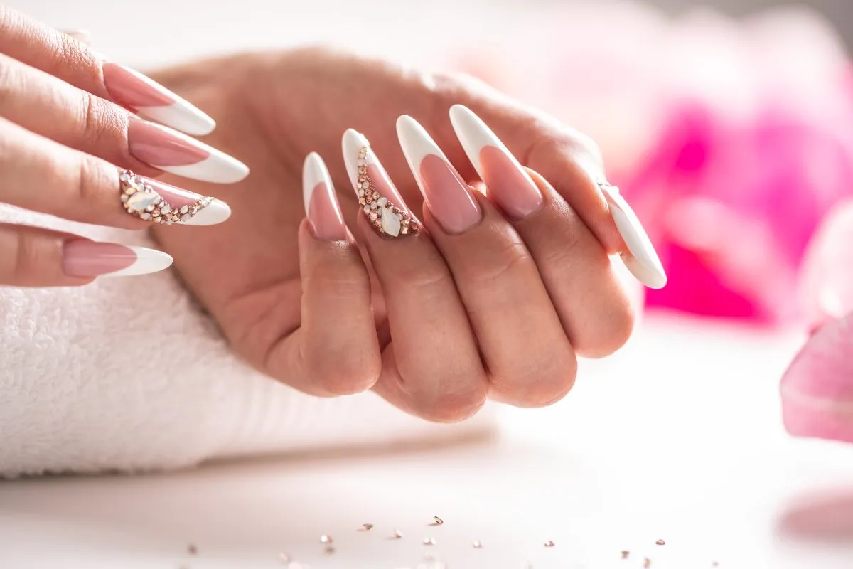 Hands showcasing bejeweled deep French manicure